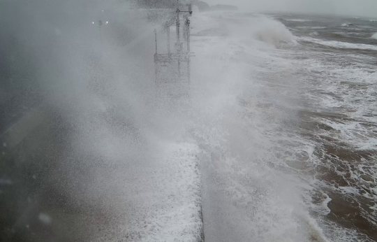 Photo of waves overtopping sea defences.